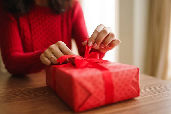 Female hands opening red gift box. Unpacking a gift. Valentines day celebration concept. Relationship, surprise and love concept.