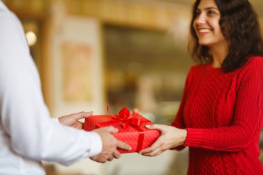 Adam karısına kırmızı kurdeleli bir hediye kutusu veriyor. Sevgi dolu bir çift restoranda sarılıp sevgililer gününü kutluyor. Sevgililer Günü, tatil ve sürpriz konsept. İlişki ve aşk.