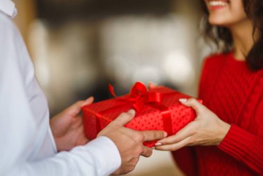 Adam karısına kırmızı kurdeleli bir hediye kutusu veriyor. Sevgi dolu bir çift restoranda sarılıp sevgililer gününü kutluyor. Sevgililer Günü, tatil ve sürpriz konsept. İlişki ve aşk.