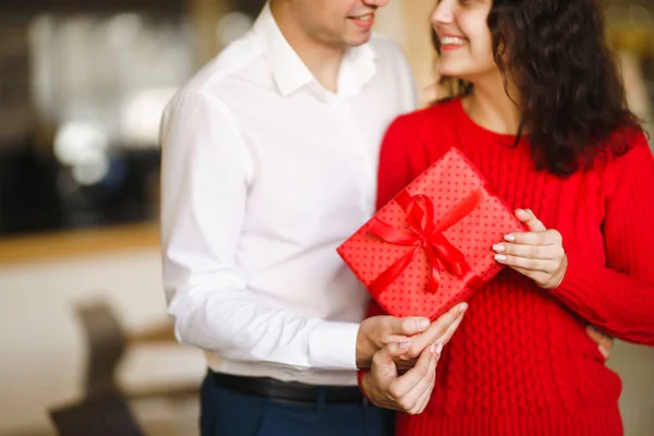 男人送给女人一个红丝带礼品盒 一对恋人拥抱在一起 在餐厅里庆祝情人节 情人节 节日和惊喜的概念 关系和爱情 — 图库照片