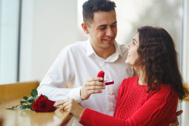 Yakışıklı bir adam restoranda güzel bir kadına evlenme teklif ediyor. Çekici bir kadının evlenme teklifi almasına şaşırdım. Sevgililer Günü kutlaması konsepti. İlişki ve aşk kavramı.