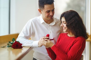 Yakışıklı bir adam restoranda güzel bir kadına evlenme teklif ediyor. Çekici bir kadının evlenme teklifi almasına şaşırdım. Sevgililer Günü kutlaması konsepti. İlişki ve aşk kavramı.