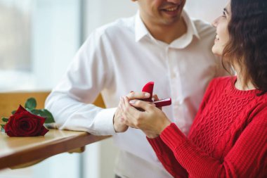 Yakışıklı bir adam restoranda güzel bir kadına evlenme teklif ediyor. Çekici bir kadının evlenme teklifi almasına şaşırdım. Sevgililer Günü kutlaması konsepti. İlişki ve aşk kavramı.