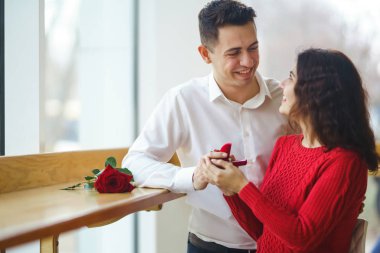 Yakışıklı bir adam restoranda güzel bir kadına evlenme teklif ediyor. Çekici bir kadının evlenme teklifi almasına şaşırdım. Sevgililer Günü kutlaması konsepti. İlişki ve aşk kavramı.