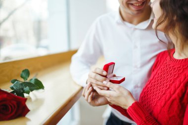 Yakışıklı bir adam restoranda güzel bir kadına evlenme teklif ediyor. Çekici bir kadının evlenme teklifi almasına şaşırdım. Sevgililer Günü kutlaması konsepti. İlişki ve aşk kavramı.