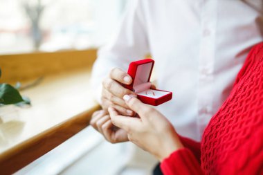 Yakışıklı bir adam restoranda güzel bir kadına evlenme teklif ediyor. Çekici bir kadının evlenme teklifi almasına şaşırdım. Sevgililer Günü kutlaması konsepti. İlişki ve aşk kavramı.