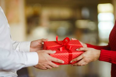 Sevgililer Günü, tatil ve sürpriz konsept. Erkek, kadınına kırmızı bir hediye kutusu verir. Tatlı çift yıldönümlerini kutluyor. İlişki ve aşk kavramı.