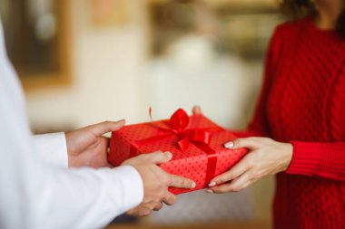 Sevgililer Günü, tatil ve sürpriz konsept. Erkek, kadınına kırmızı bir hediye kutusu verir. Tatlı çift yıldönümlerini kutluyor. İlişki ve aşk kavramı.