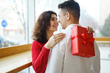 Hediye kucaklaşması olan mutlu çift. Birbirine aşık bir çiftin elinde kırmızı hediye kutusu. Sevgililer Günü, tatil ve sürpriz konsept. Sevgililer birbirlerine hediyeler verir. İlişki ve aşk kavramı.