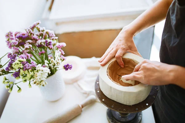 Hands sculpts a cup from clay pot. Woman working on the potter's wheel. Workshop on modeling on the potter's wheel. Handmade consept.