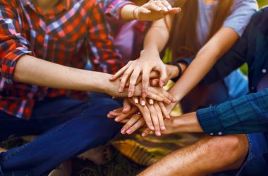 Gençler ellerini birleştiriyor. Gençler yaz parkında birlikte eğleniyorlar. Bir grup genç eğleniyor. Dinlenme, eğlence, yaz, tatil konsepti.
