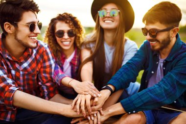 Gençler ellerini birleştiriyor. Gençler yaz parkında birlikte eğleniyorlar. Bir grup genç eğleniyor. Dinlenme, eğlence, yaz, tatil konsepti.