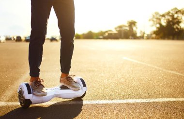 İnsan bacakları jimnastik tahtasında. Beyaz uçan kaykaylı biri. Elektrikli hiroskoper sürücüsü. Kendi kendini dengeleyen iki tekerlekli sörf tahtası ya da kaykay scooterı.