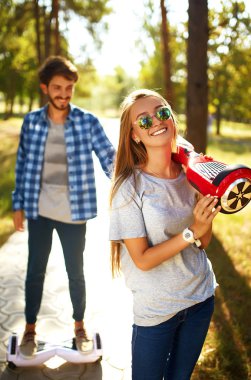 Mutlu adam ve kadın şehirde birlikte rahatlamak için Hoverboard 'a biniyorlar. Parkta uçan kaykaya binen genç bir çift, dengeli scooter kullanıyorlar. Aktif yaşam tarzı teknolojisi gelecek.