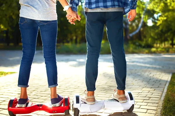 市内の屋外で一緒にリラックスした時間を過ごすためにホバーボードに乗っている男女の足 公園でホバーボードに乗っている若いカップル 自己バランススクーター アクティブライフスタイルテクノロジーの未来 — ストック写真