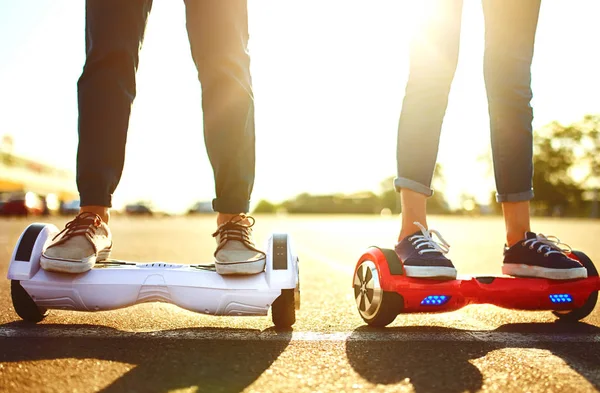 Legs of man and woman riding on the Hoverboard for relaxing time together outdoor at the city. A young couple riding a hoverboard in a park, self-balancing scooter. Active lifestyle technology future.