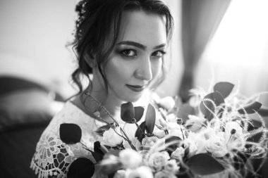 Zarif genç gelin portresi. Gelinin sabahı. Düğün sabahı gelin buketi olan beyaz gelinlik içinde güzel bir gelin. Profesyonel makyajlı ve saç stili olan mutlu kadın.. 