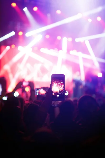 携帯電話のレコードライブ音楽祭で手 公演中にスマートフォンで写真を撮る人たち 観客は手を挙げて踊り コンサートを楽しんでいます — ストック写真