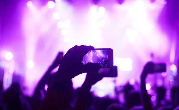 携帯電話のレコードライブ音楽祭で手 公演中にスマートフォンで写真を撮る人たち 観客は手を挙げて踊り コンサートを楽しんでいます — ストック写真