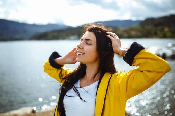 若い女性はノルウェーの山々を背景に自由を楽しんでいます 雄大な山々を見て黄色のジャケットの少女観光客 ライフスタイル コンセプト — ストック写真