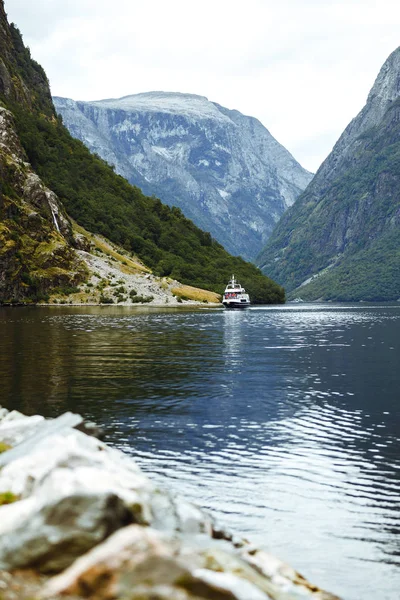 Norveç fiyortlarında yelken açan bir gemi. Fiyort ve dağlarla inanılmaz doğa manzarası. Güzel bir yansıma. Seyahat, yaşam tarzı, macera, vahşi doğa konsepti.