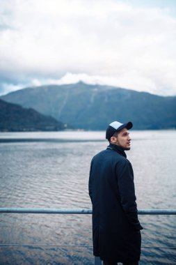 Norveç 'teki dağların arka planında poz veren genç adam. Güzel dağ gölüne yürüyüş yapan bir turist. Seyahat, yaşam tarzı, macera, konsept.