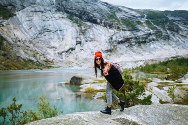 Tarz sahibi genç bir kadın Norveç 'teki dağların arka planında özgürlüğün tadını çıkarıyor. Kız turist güzel manzaralı görkemli dağların tadını çıkarıyor. Seyahat, yaşam tarzı, macera, konsept.