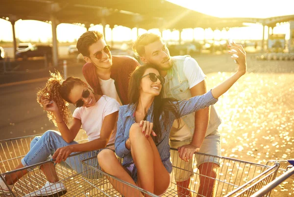Fiatal Barátok Szórakoznak Bevásárlókocsikon Szelfit Készítenek Telefonban Egy Csapat Boldog — Stock Fotó