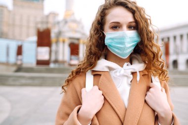 Sokakta yüzü koruyucu steril tıbbi maske takmış bir kız. Kadın, yüz maskesi tak, karantina şehrinde virüs, salgın ve salgın hastalıklardan koru. Corona virüsü.
