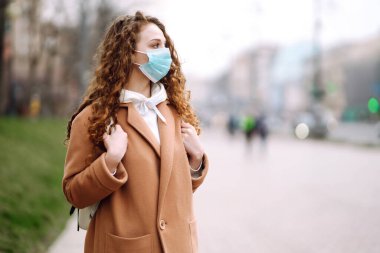 Sokakta yüzü koruyucu steril tıbbi maske takmış bir kız. Kadın, yüz maskesi tak, karantina şehrinde virüs, salgın ve salgın hastalıklardan koru. Corona virüsü.
