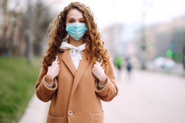 Sokakta yüzü koruyucu steril tıbbi maske takmış bir kız. Kadın, yüz maskesi tak, karantina şehrinde virüs, salgın ve salgın hastalıklardan koru. Corona virüsü.