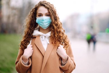 Sokakta yüzü koruyucu steril tıbbi maske takmış bir kız. Kadın, yüz maskesi tak, karantina şehrinde virüs, salgın ve salgın hastalıklardan koru. Corona virüsü.