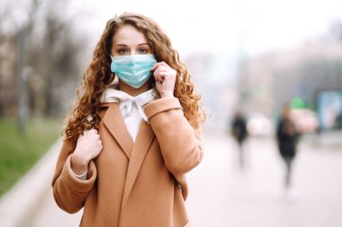 Sokakta yüzü koruyucu steril tıbbi maske takmış bir kız. Kadın, yüz maskesi tak, karantina şehrinde virüs, salgın ve salgın hastalıklardan koru. Corona virüsü.