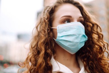 Sokakta yüzü koruyucu steril tıbbi maske takmış bir kız. Kadın, yüz maskesi tak, karantina şehrinde virüs, salgın ve salgın hastalıklardan koru. Corona virüsü.