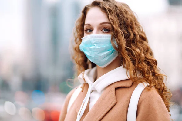 Sokakta yüzü koruyucu steril tıbbi maske takmış bir kız. Kadın, yüz maskesi tak, karantina şehrinde virüs, salgın ve salgın hastalıklardan koru. Corona virüsü.