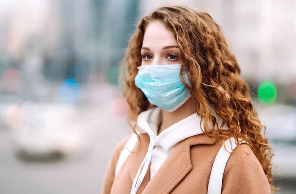 Sokakta yüzü koruyucu steril tıbbi maske takmış bir kız. Kadın, yüz maskesi tak, karantina şehrinde virüs, salgın ve salgın hastalıklardan koru. Corona virüsü.