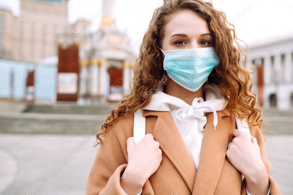 Girl in protective sterile medical mask on her face on the street. Woman, wear face mask, protect from infection of virus, pandemic, outbreak and epidemic of disease in  quarantine city. Corona virus.