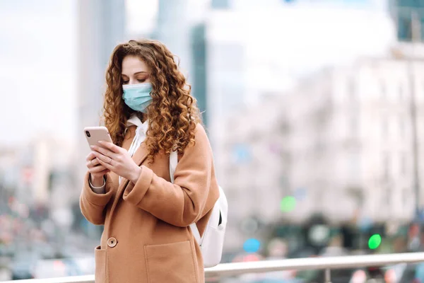 도시에서 의료용 마스크를 소녀가 핸드폰을 있습니다 뉴스를 전화를 사용하는 전염병의 — 스톡 사진