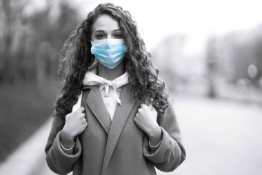 Koruyucu steril tıbbi maske takan siyah beyaz bir kız. Kadın, yüz maskesi tak, karantina şehrinde virüs, salgın ve salgın hastalıklardan koru.. 