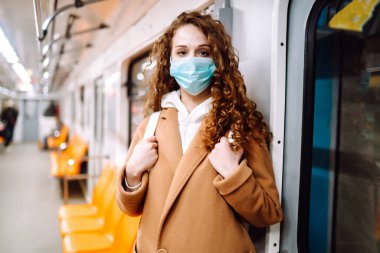 Metro vagonunda steril tıbbi maskeli bir kız. Kadın, yüz maskesi tak, karantina şehrinde virüs, salgın ve salgın hastalıklardan koru.. 