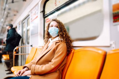 Metro vagonunda steril tıbbi maskeli bir kız. Kadın, yüz maskesi tak, karantina şehrinde virüs, salgın ve salgın hastalıklardan koru.. 