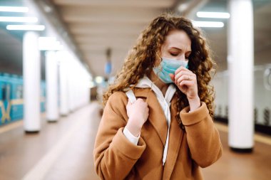 Korunaklı steril tıbbi maskeli kız metro istasyonunda öksürüyor. Kadın, yüz maskesi tak, karantina şehrinde virüs, salgın ve salgın hastalıklardan koru.. 