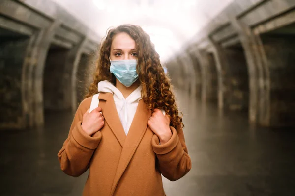 在空荡荡的地铁站 脸上戴着无菌防护口罩的女孩 女用面罩 在检疫城市防止病毒感染 大流行 疾病爆发和流行 — 图库照片