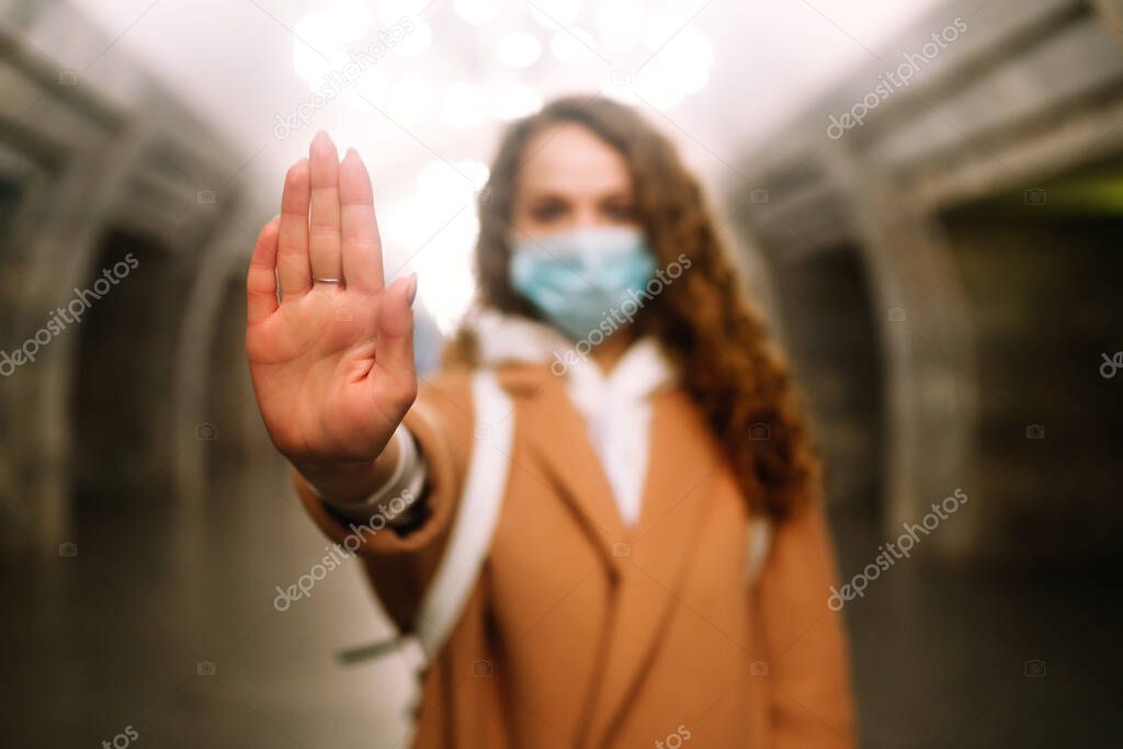 Girl in protective sterile medical mask on her face at empty subway station. Woman, wear face mask, protect from infection of virus, pandemic, outbreak and epidemic of disease in quarantine city. 