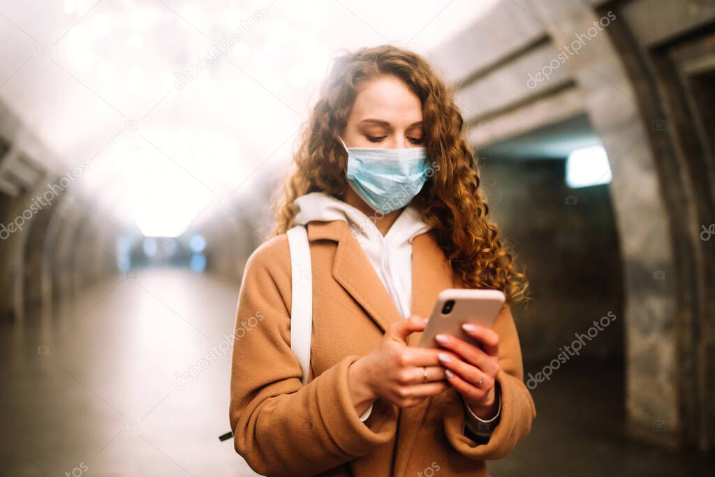 Girl in protective sterile medical mask on her face at empty subway station. Woman, wear face mask, protect from infection of virus, pandemic, outbreak and epidemic of disease in quarantine city. 