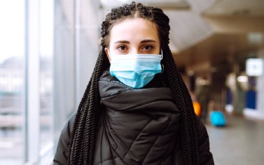 Karantina şehrinde yüzü steril tıbbi maske takmış bir kız. Kadın, yüz maskesi tak, karantina bölgesinde virüs, salgın ve salgın hastalıklardan koru. Covid 19.