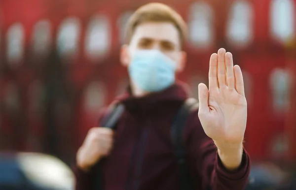Hand stop sign. Men in a sterile medical mask on her face, shows stop hands gesture for stop coronavirus outbreak. The concept of preventing the spread of the epidemic.