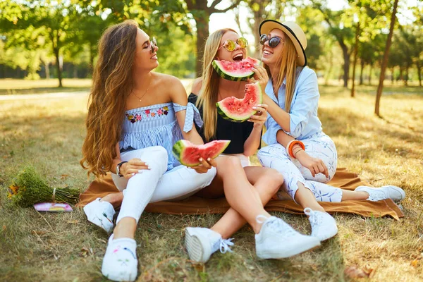 3人の美しい若い女の子が一緒に楽しみ 暑い夏の日にスイカを食べています 友人はスイカのスライスを保持し 公園にポーズ 夏のコンセプト — ストック写真