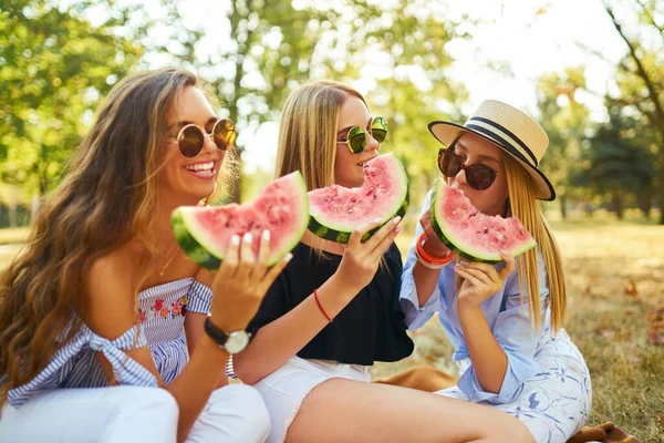 三个年轻貌美的姑娘在炎炎夏日一起玩乐 吃西瓜 朋友们拿着一片西瓜在公园里摆姿势 夏季概念 — 图库照片