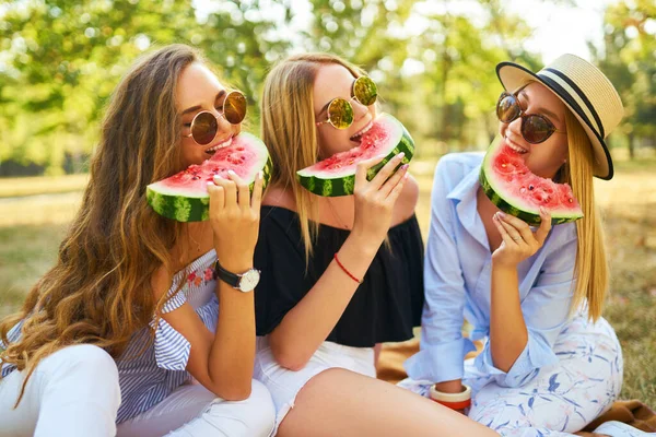 三个年轻貌美的姑娘在炎炎夏日一起玩乐 吃西瓜 朋友们拿着一片西瓜在公园里摆姿势 夏季概念 — 图库照片